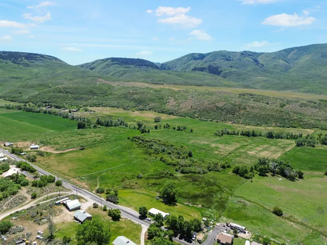 Expansive rural landscape featuring lush green fields and distant tree-covered mountains