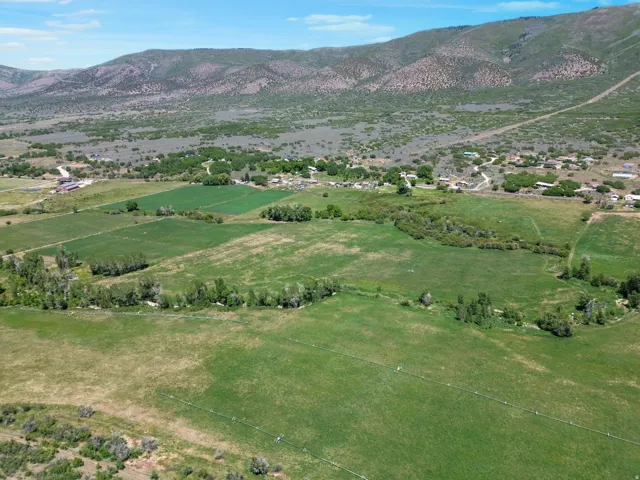 Expansive agricultural landscape featuring green fields, natural waterways, and mountain ranges
