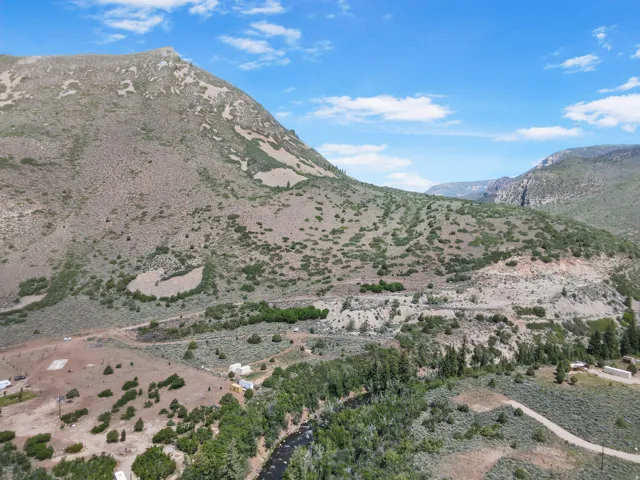 Expansive mountain landscape featuring a river, diverse natural vegetation, and a clear blue sky