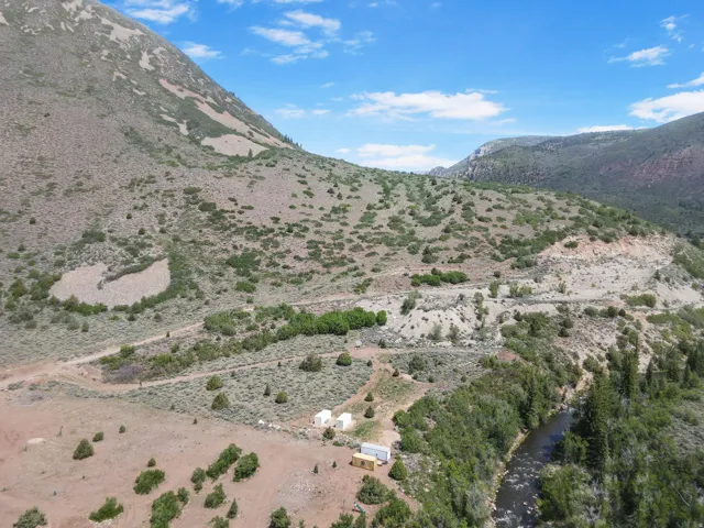 Expansive mountainous terrain featuring a river, dense foliage, and open land