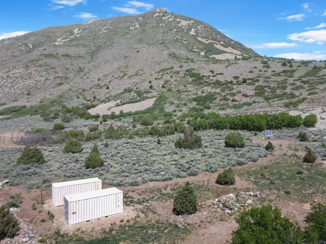 Expansive mountain landscape featuring natural vegetation and two white storage containers