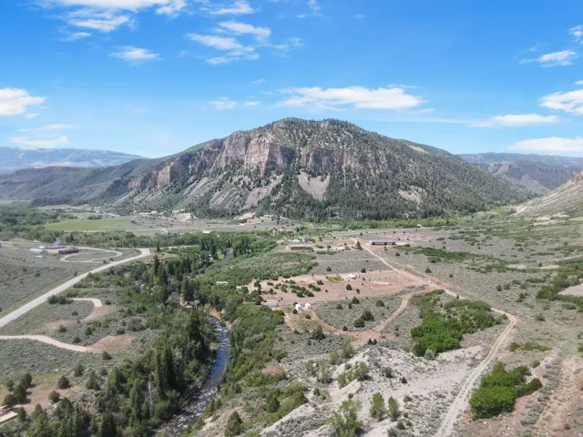 Expansive mountain landscape featuring a prominent rocky mountain formation, a winding river, and multiple structures