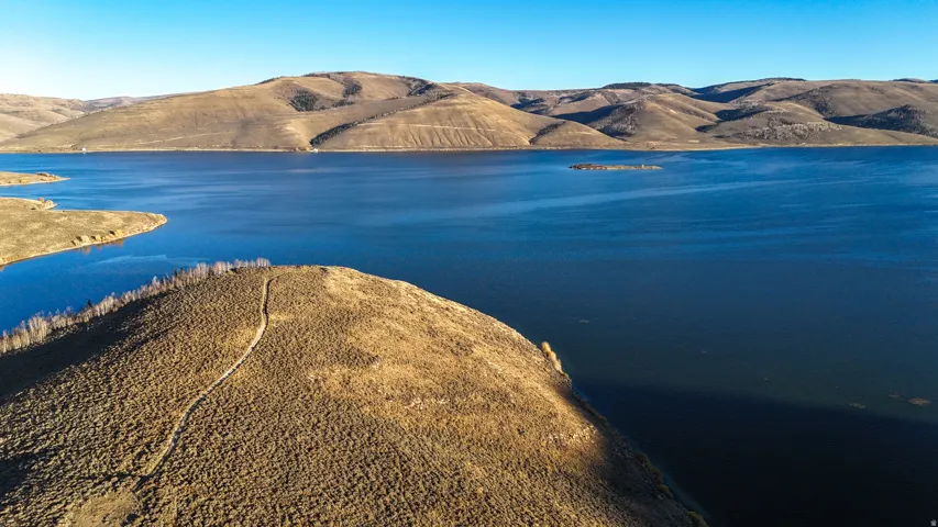 Expansive waterfront property featuring a large body of water, natural terrain, and distant hills