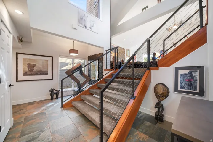 Staircase with cable railing system and wood-finish handrail, featuring carpeted treads