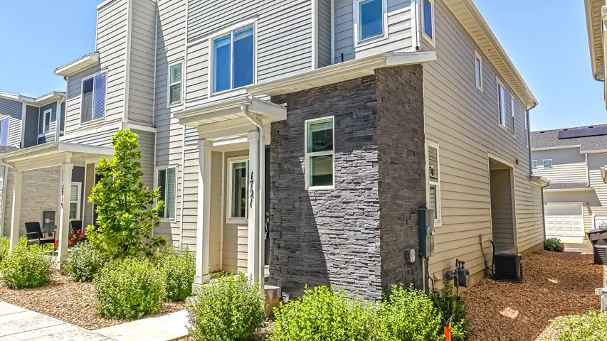 Contemporary townhome exterior featuring light-colored siding and stone veneer accents