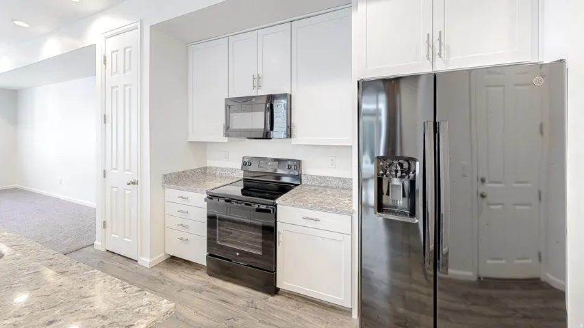 Kitchen featuring white cabinetry, light-toned countertops, wood-finish flooring, and a stainless steel side-by-side refrigerator