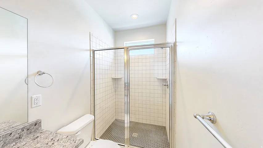 Bathroom featuring a glass-enclosed shower with white subway tile surround and dark hexagonal floor tiles