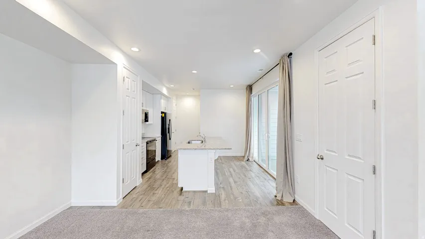 Open-concept living space with recessed lighting and light-toned carpet flooring