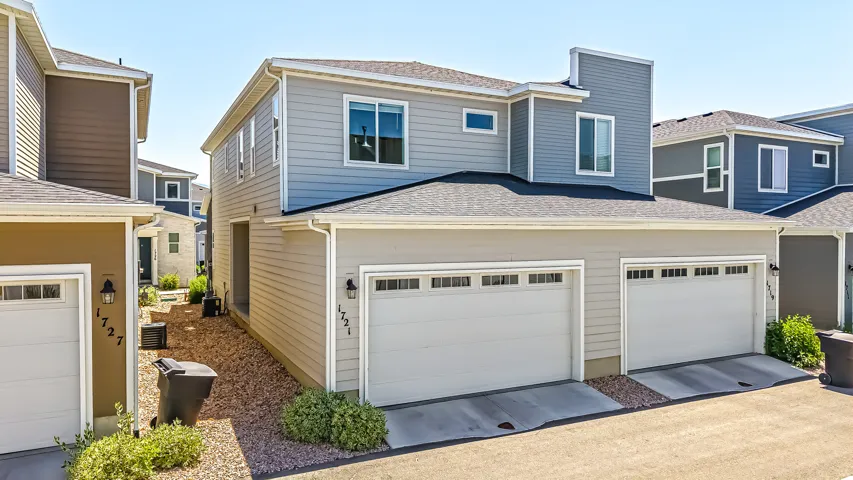 Contemporary facade featuring light gray siding, a two-car garage with panel windows, and a contrasting blue second story with multiple windows