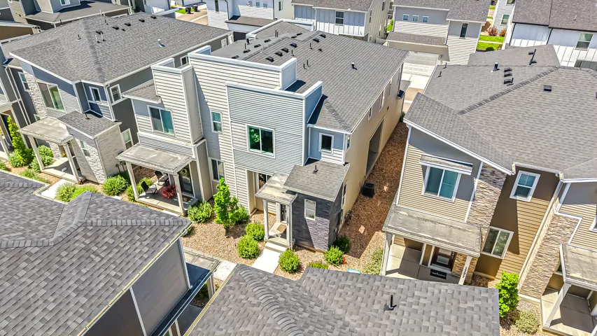 Contemporary multi-level residence featuring a diverse material palette including horizontal siding and vertical paneling, with prominent dark shingle roofing