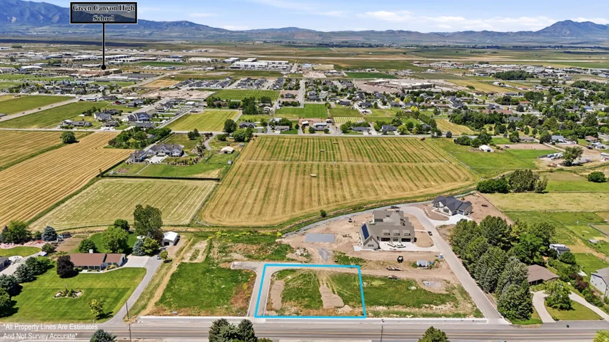 Expansive aerial perspective showcasing a residential lot outlined in blue, positioned along a paved road