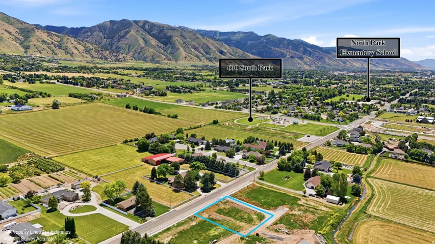Expansive land parcel featuring a rectangular lot outline, surrounded by verdant fields and distant mountains