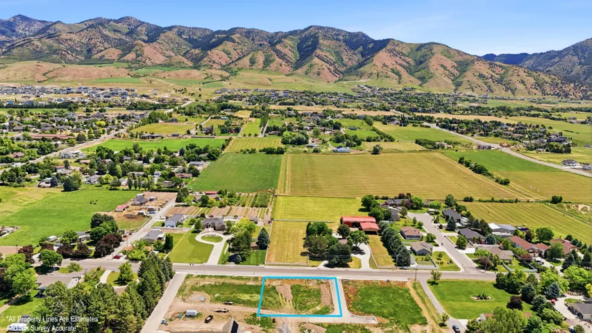 Aerial perspective highlighting a building lot with surrounding residential properties, agricultural land, and distant mountains