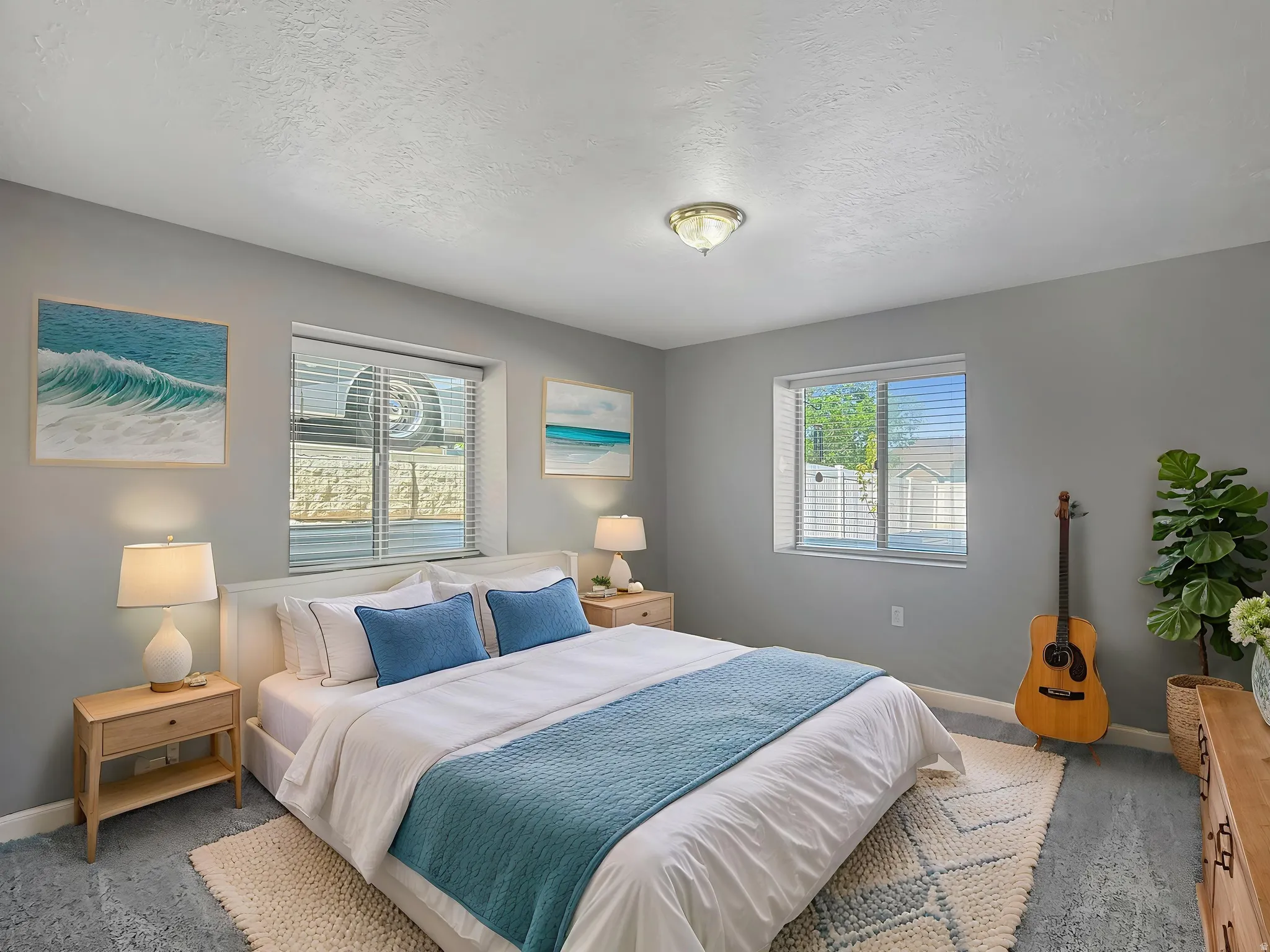 Spacious bedroom featuring light gray walls, two windows with blinds, a ceiling-mounted light fixture, and textured flooring