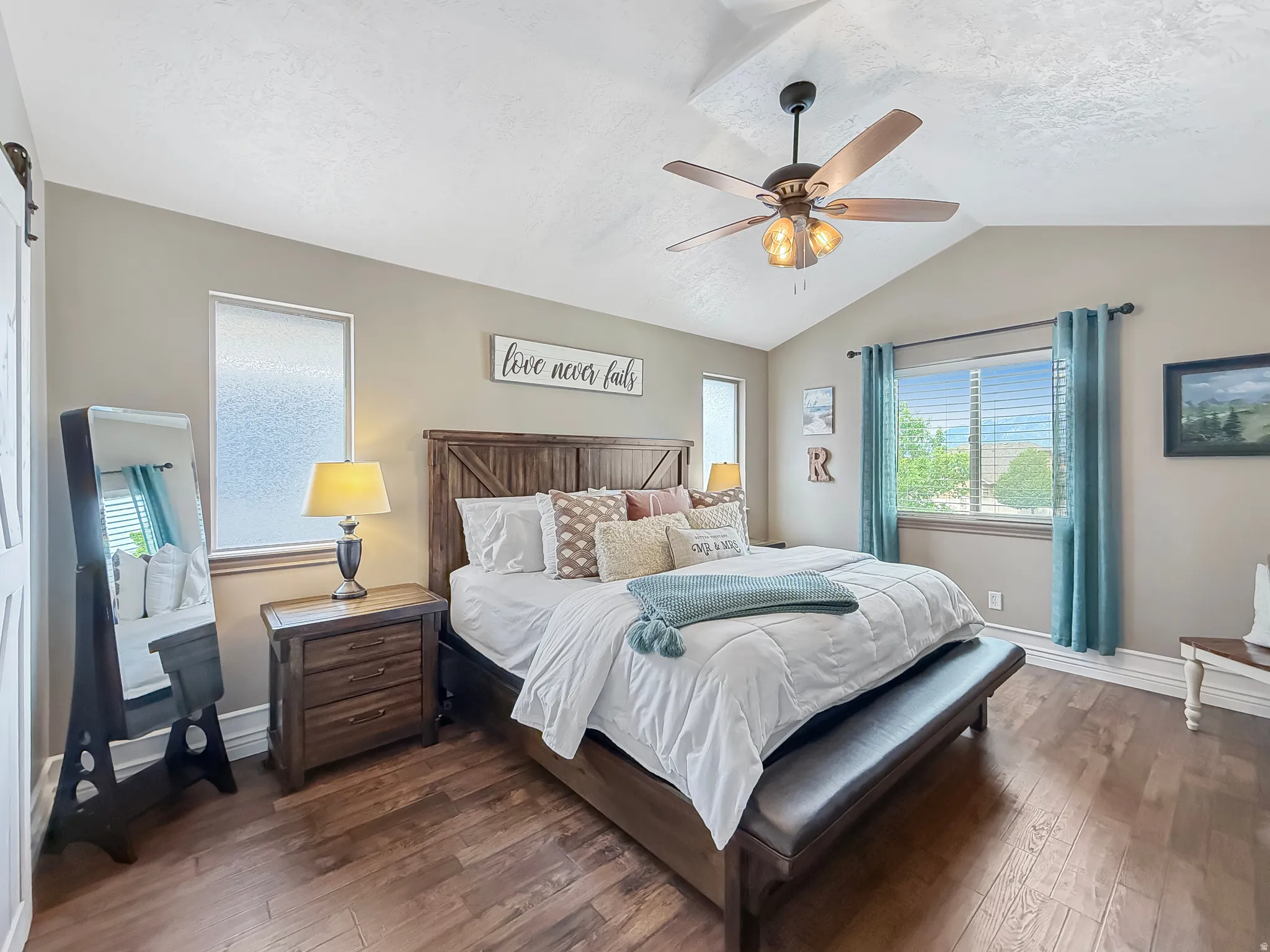Spacious bedroom featuring wood-finish flooring, a vaulted ceiling, and a ceiling fan with integrated lighting