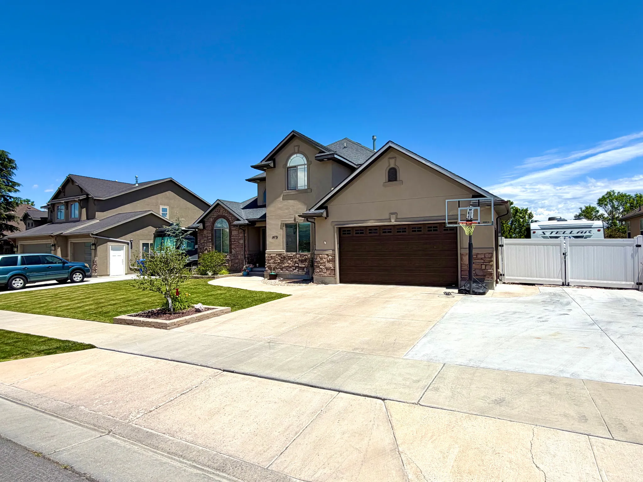 Contemporary stucco and stone exterior featuring an arched window, a two-car garage with a dark wood-finish door, and a concrete driveway