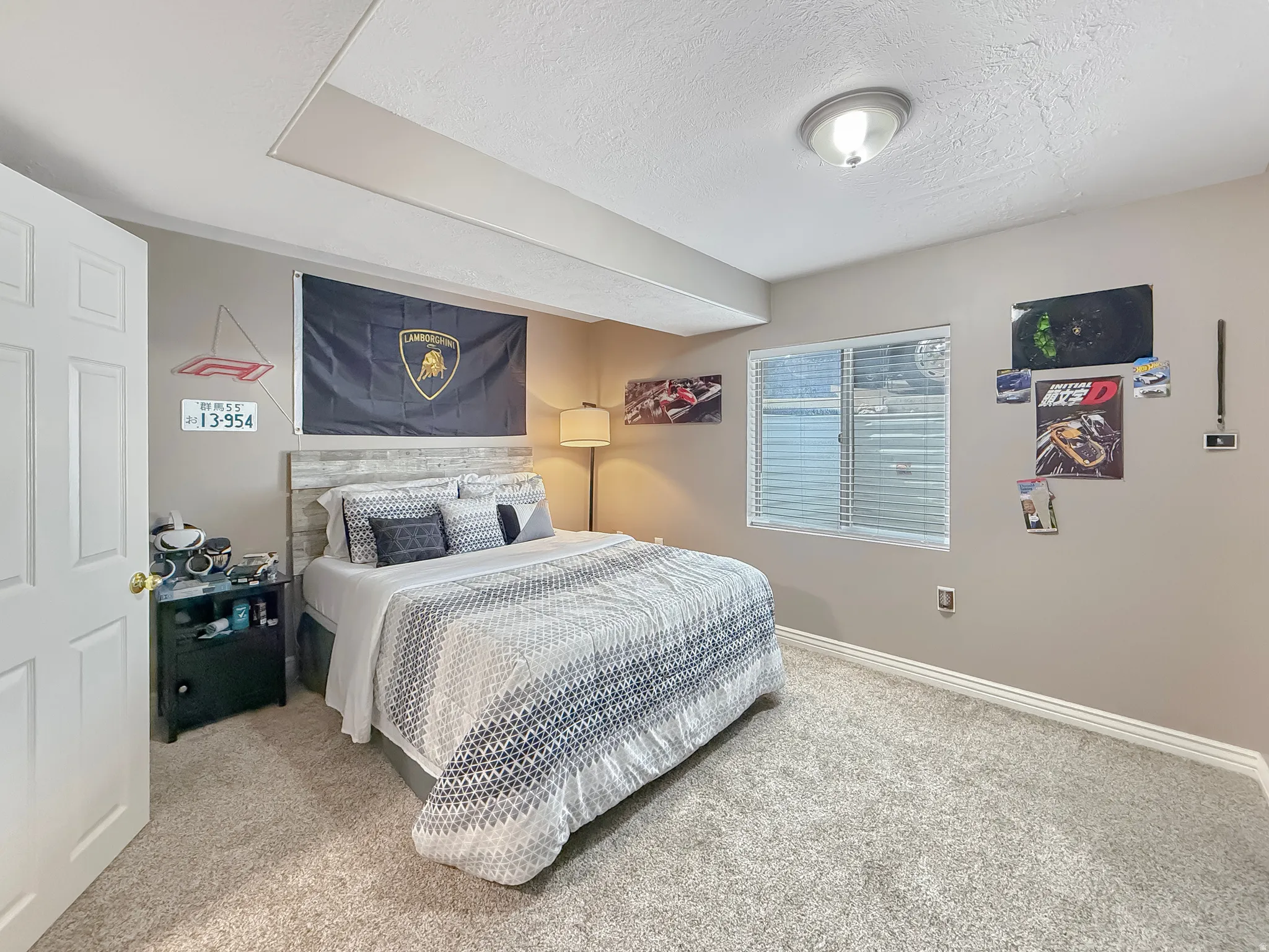 Bedroom featuring light grey carpeting, neutral wall tones, a window with blinds, and a white paneled door