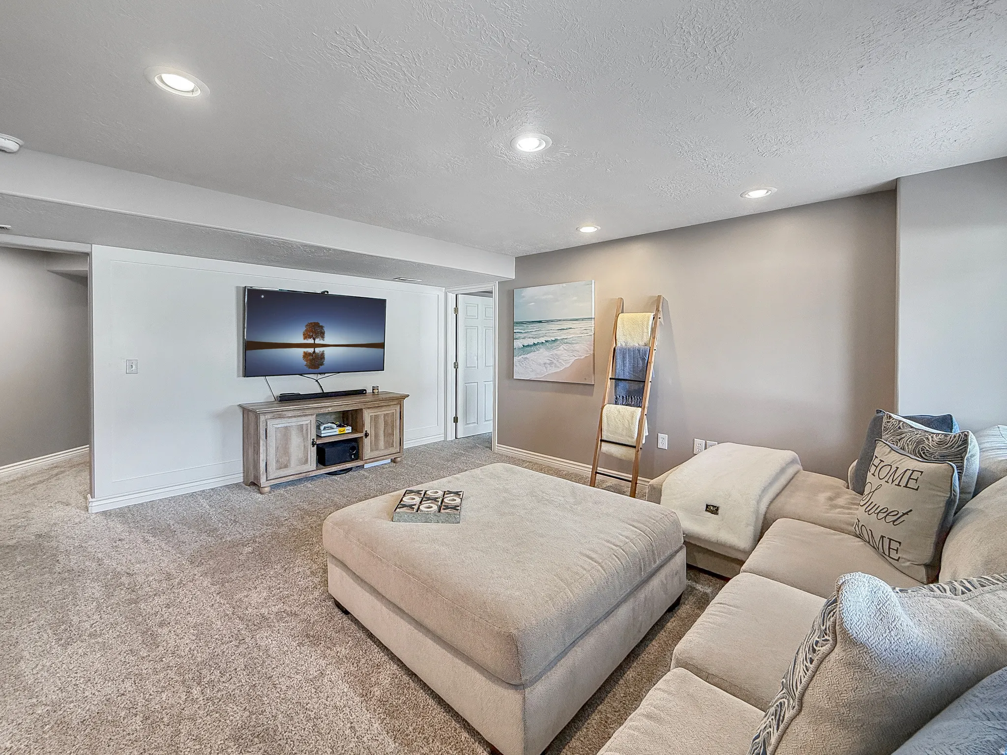 Recessed lighting illuminates the carpeted living area with light-toned walls