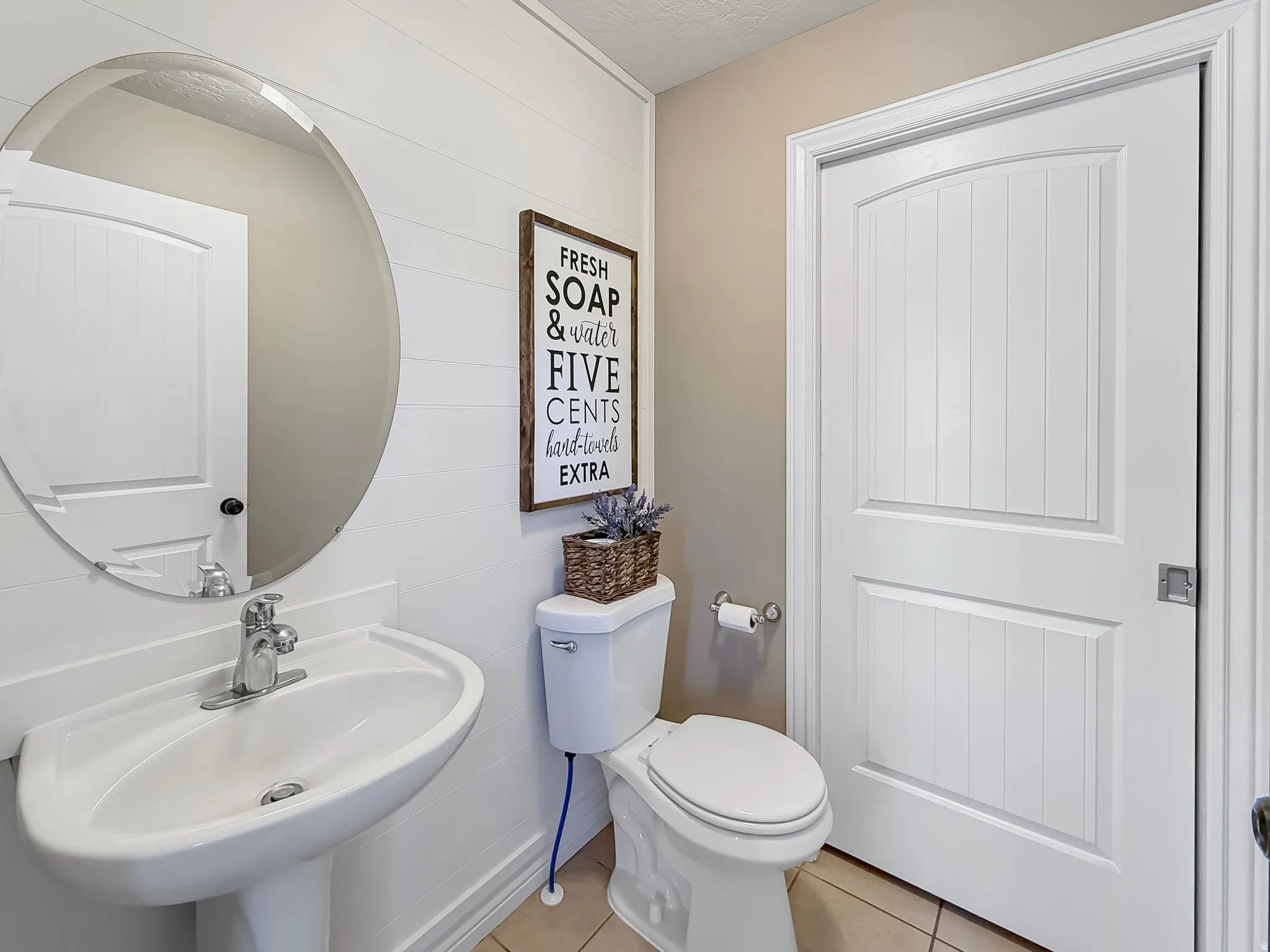 Pedestal sink with chrome faucet, complemented by an oval mirror