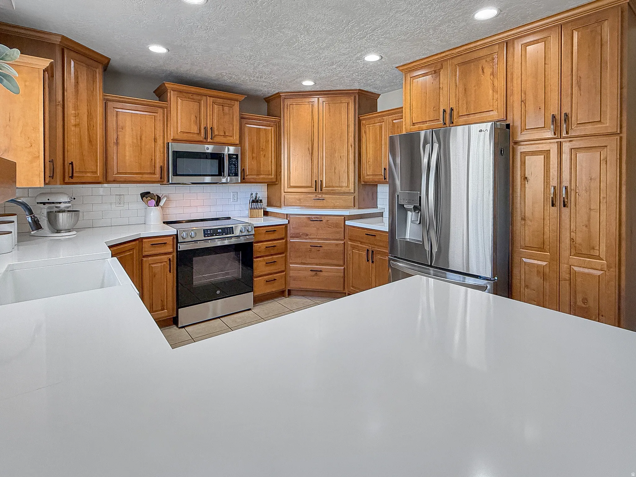 Kitchen featuring extensive wood cabinetry, white countertops, stainless steel appliances, and a subway tile backsplash