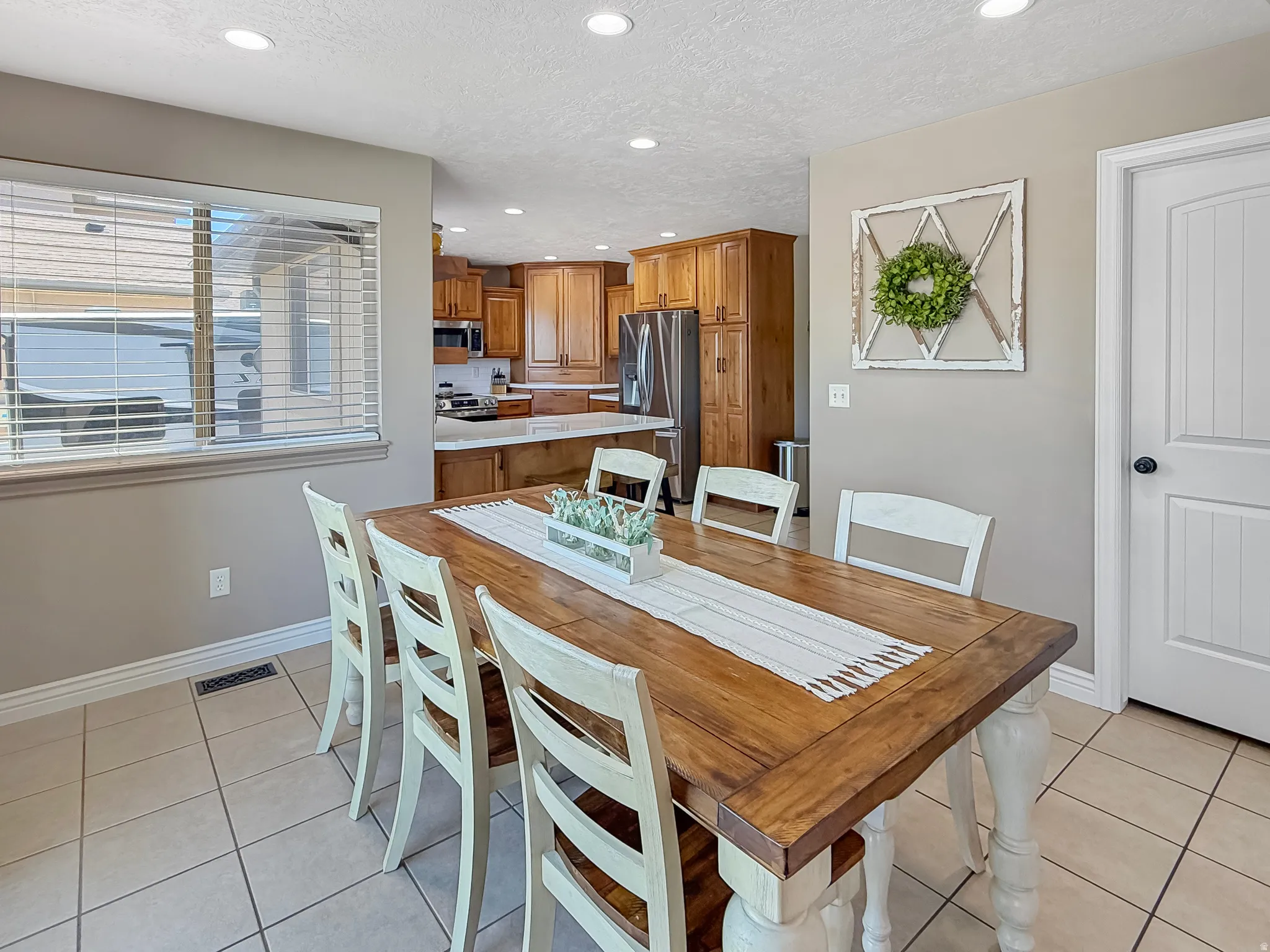 Dining area featuring tile flooring, a window with horizontal blinds, recessed lighting, and a paneled interior door