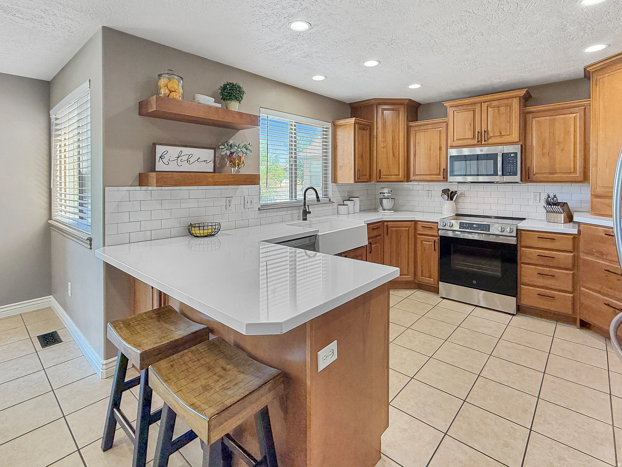 Contemporary kitchen featuring light wood cabinetry, white subway tile backsplash, and light-toned tile flooring