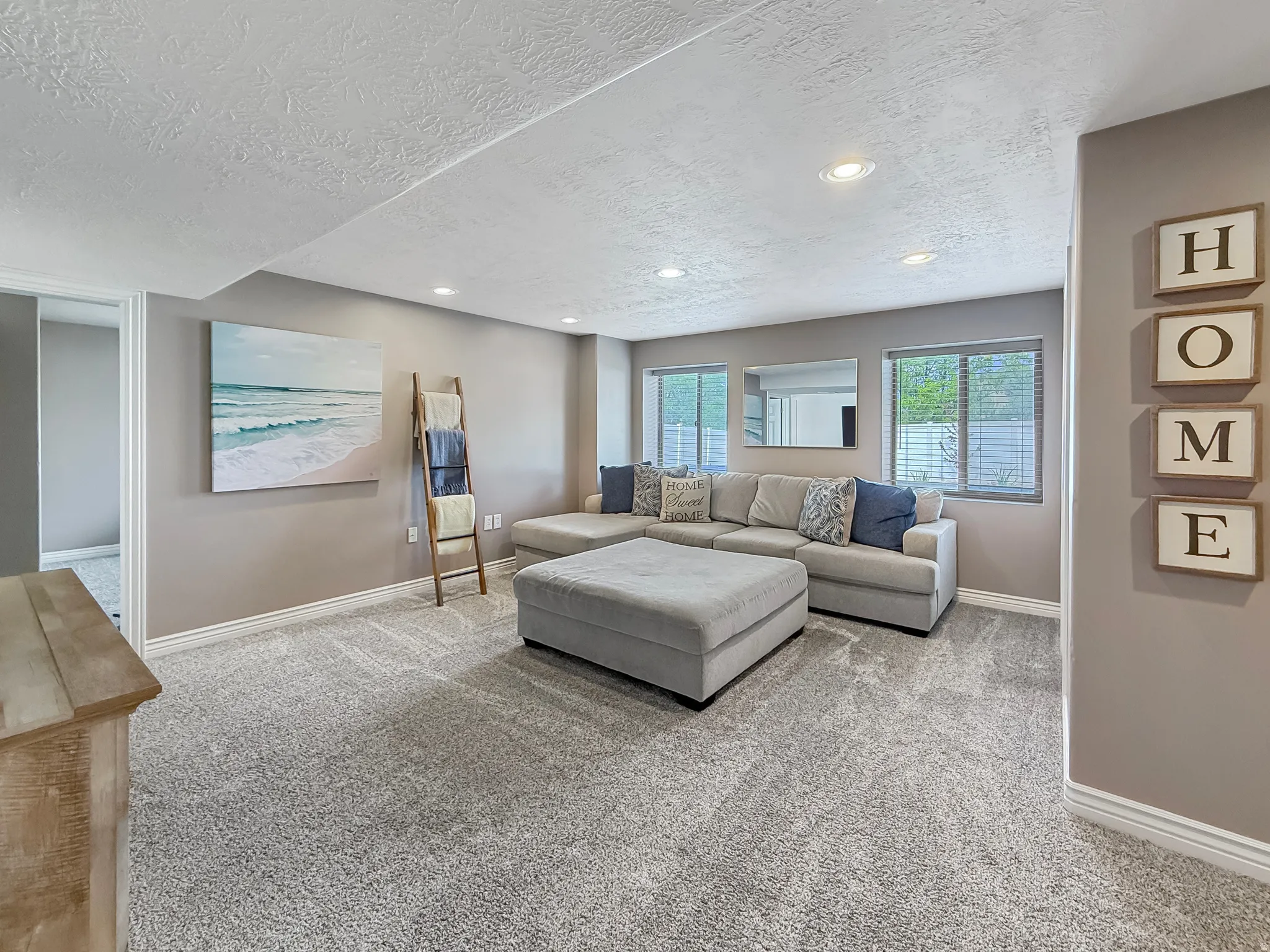 Spacious room featuring neutral-toned walls, recessed lighting, multiple windows with blinds, and light-colored carpeting