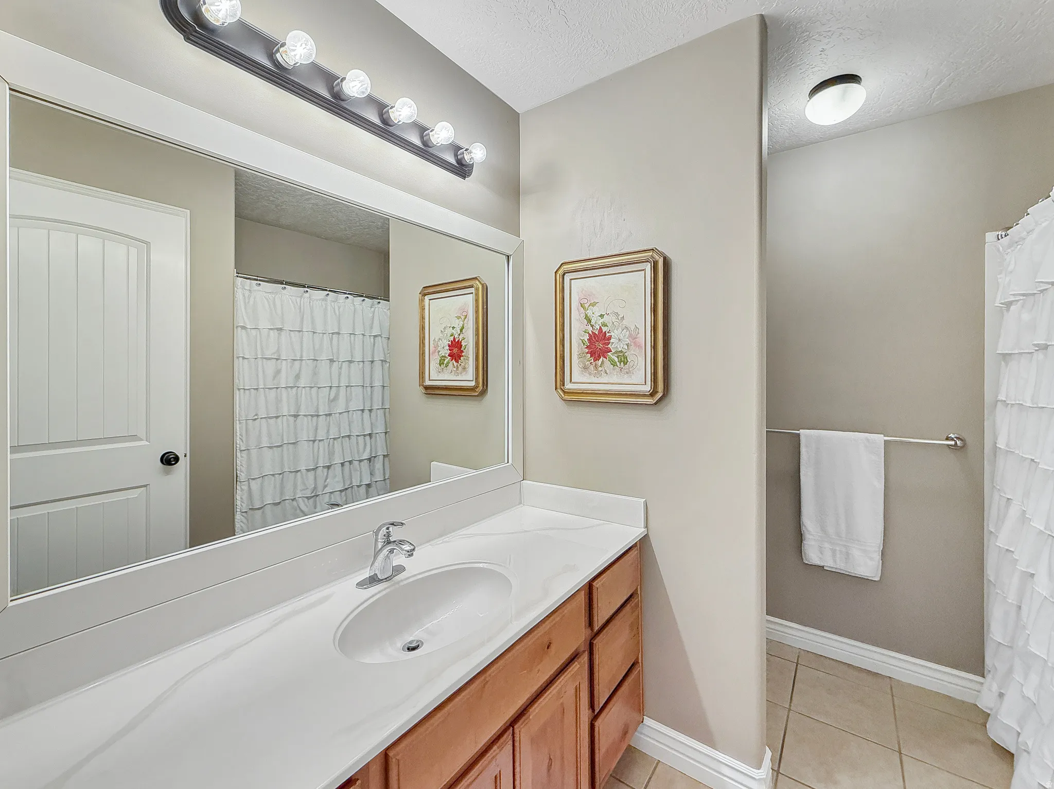 Bathroom vanity featuring a white countertop with an integrated sink, chrome faucet, and a wood-finish cabinet