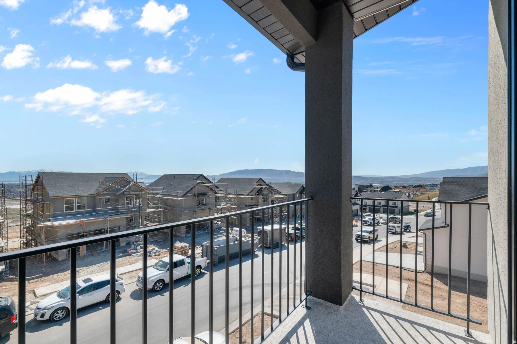 Exterior balcony with black metal railings, a dark gray structural column, and a light gray textured wall