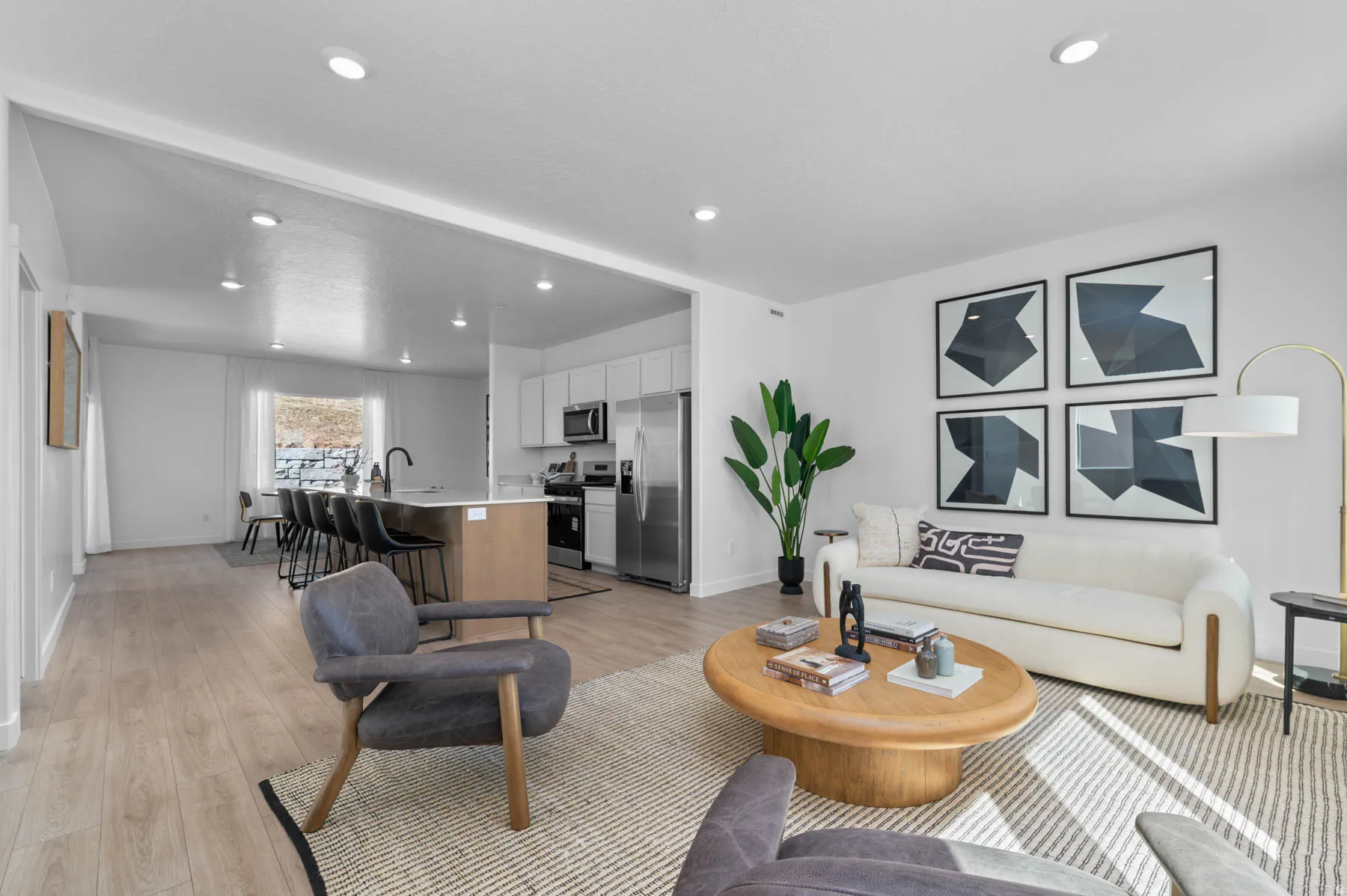Open-concept living space featuring wood-finish flooring, recessed lighting, and a kitchen with an island, light cabinetry, and stainless steel appliances