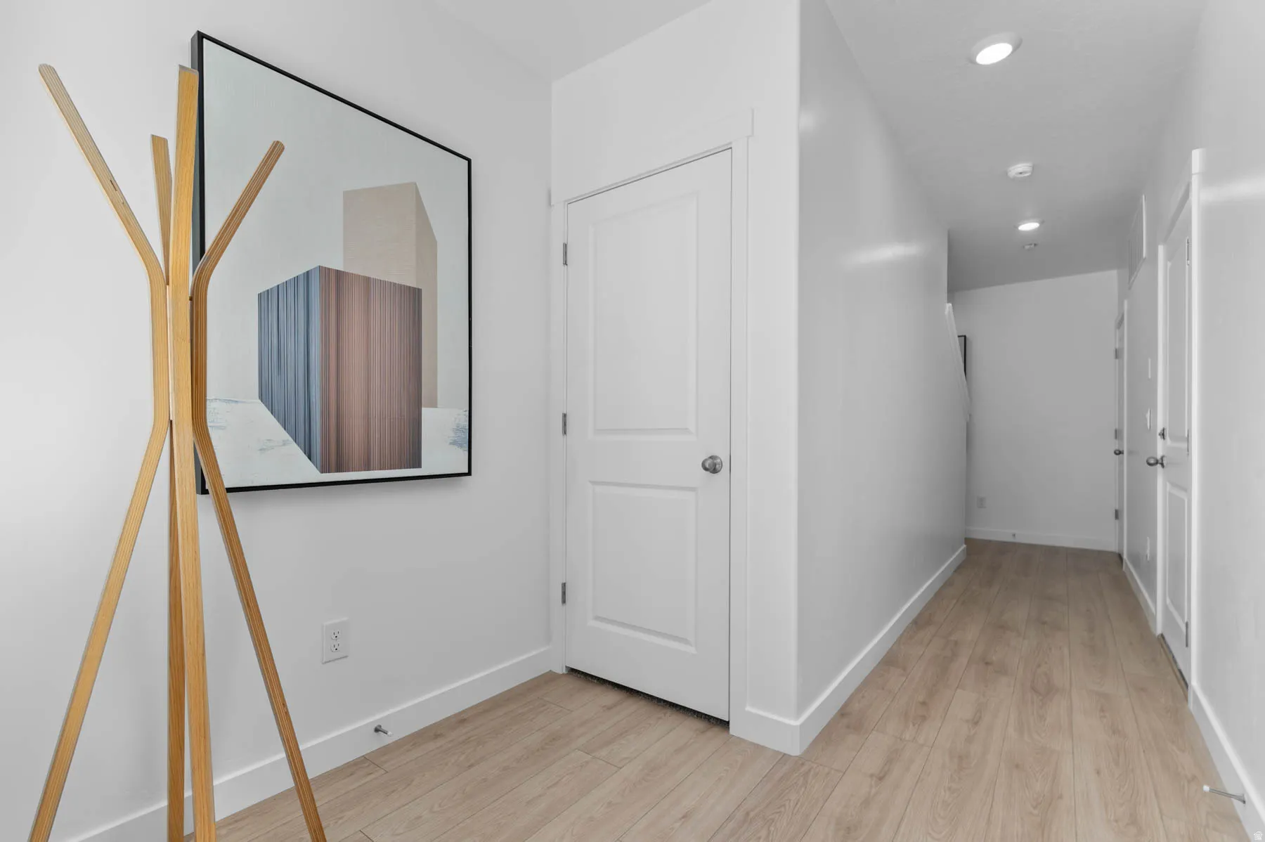 Entryway featuring wood-finish flooring, white paneled doors, and recessed lighting