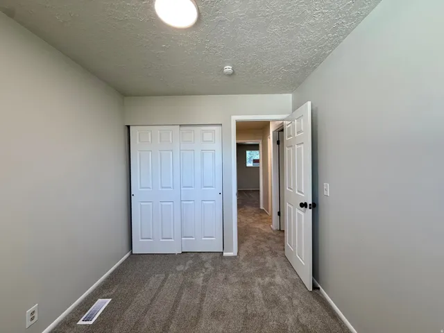 Neutral-toned interior room featuring textured ceilings and gray carpeting