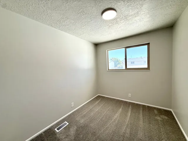 Neutral tone walls complemented by textured ceilings and brown carpeting