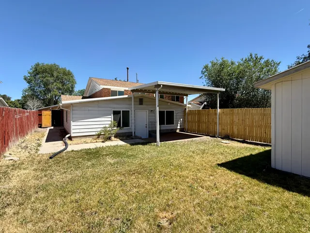 Expansive backyard space featuring a covered patio, a detached storage building, and a wood privacy fence