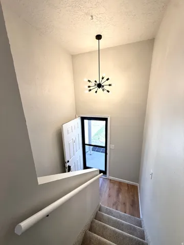 Entry foyer featuring a contemporary sputnik chandelier, wood-finish flooring, and a carpeted staircase with a white handrail