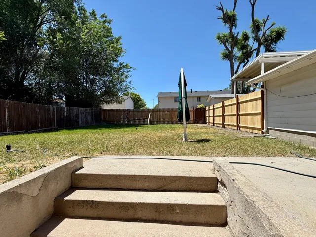 Concrete steps leading to a spacious backyard with a mix of wood fencing