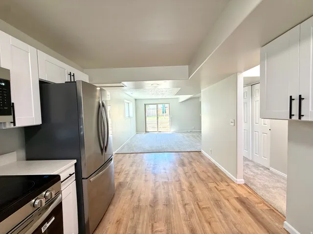 Kitchen featuring wood-finish flooring, white cabinetry with matte black hardware, and stainless steel appliances