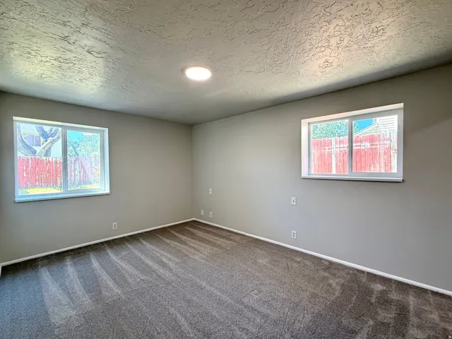 Spacious room featuring gray textured carpet and light gray wall paint