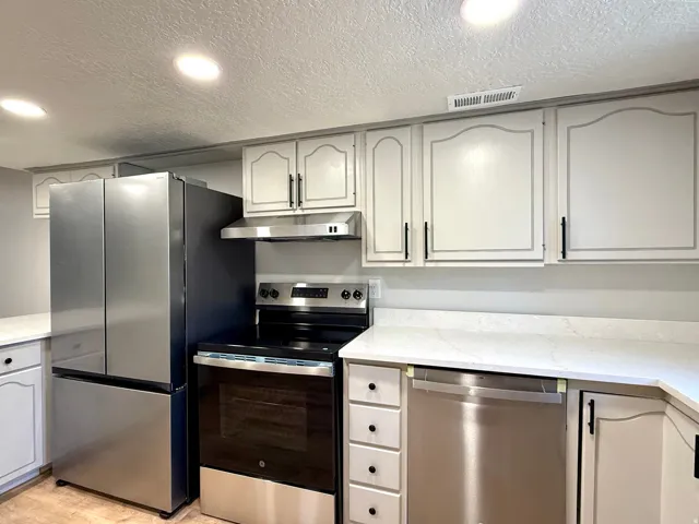 Kitchen featuring stainless steel appliances, light cabinetry with dark hardware, a white countertop, and recessed lighting