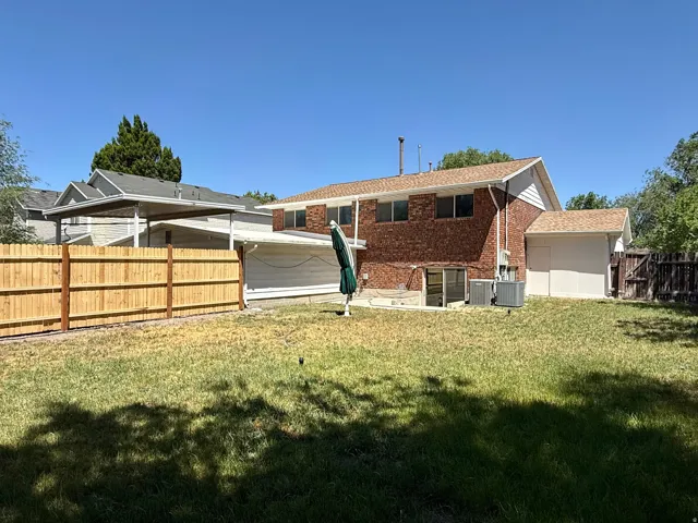 Expansive backyard featuring a new wood fence, mature trees, brick exterior, and a detached shed