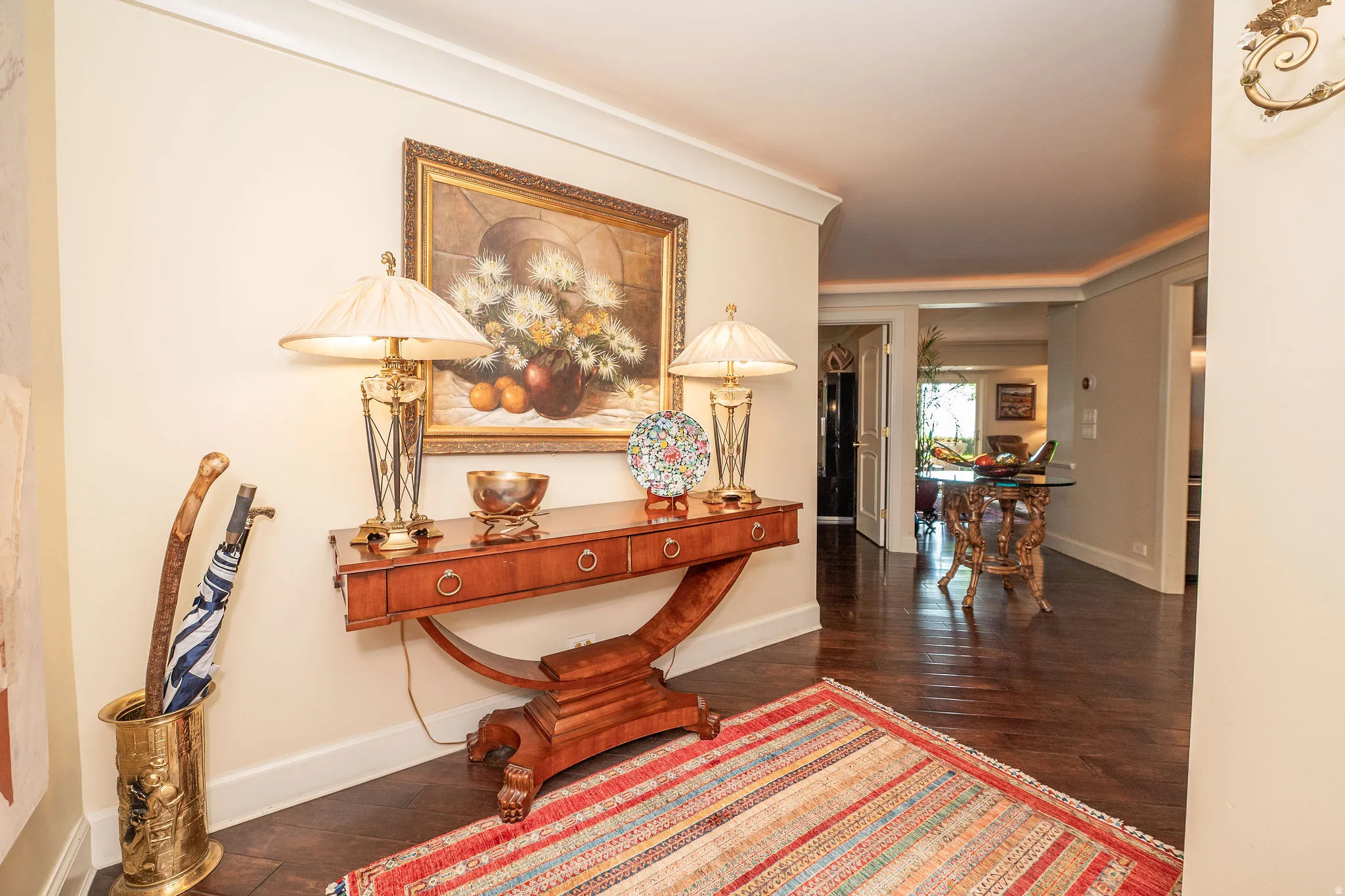 Hardwood flooring extending through a hallway with crown molding and baseboards