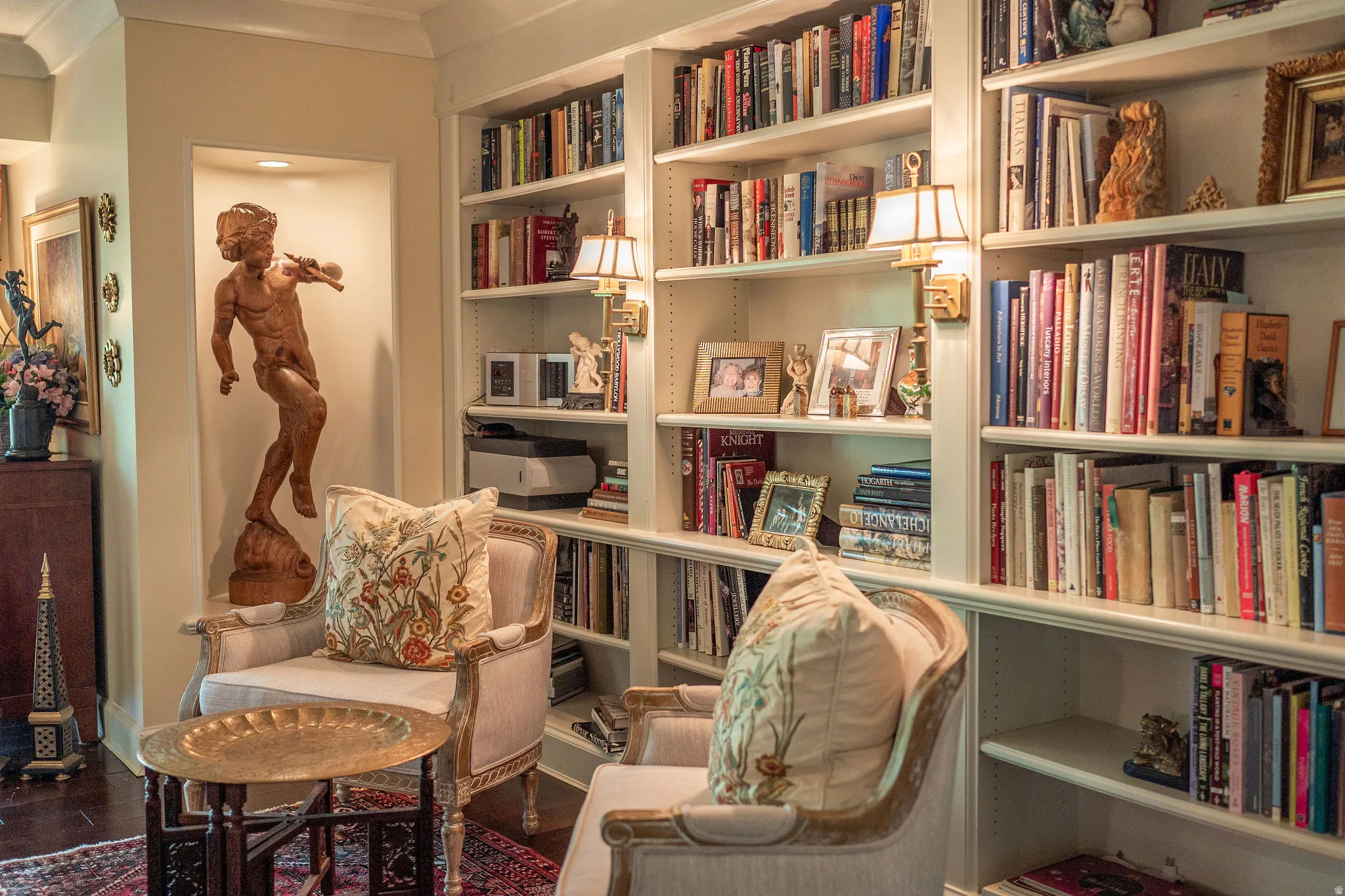 Built-in shelving features traditional wall sconces and recessed lighting in a decorative niche