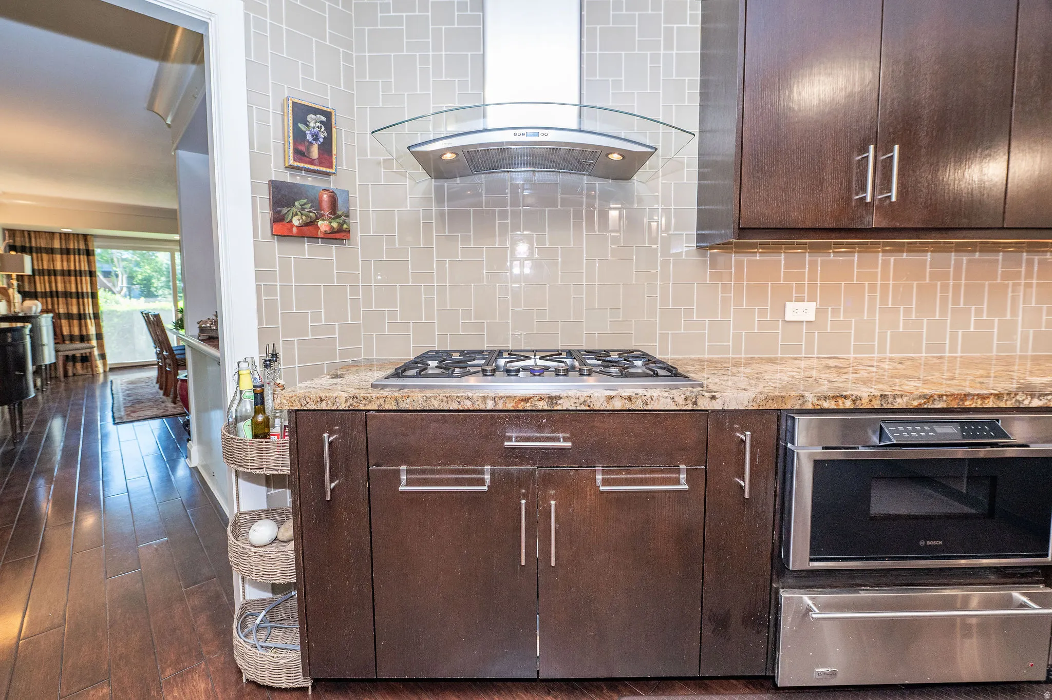 Kitchen featuring dark wood-finish cabinetry, a gas cooktop, stainless steel microwave, and stone countertops