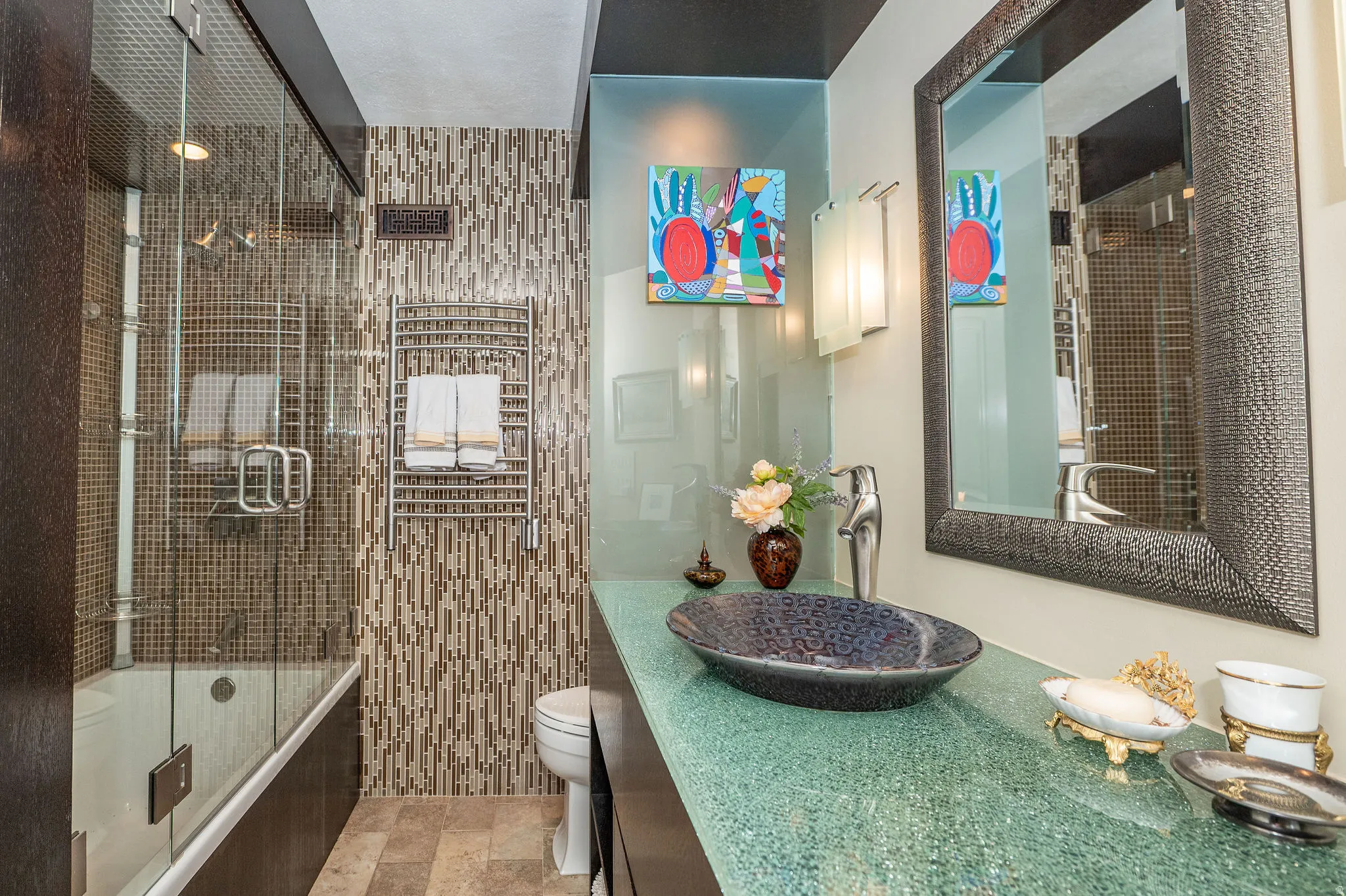 Bathroom featuring a vessel sink atop a textured green countertop, framed mirror, and contemporary wall sconces