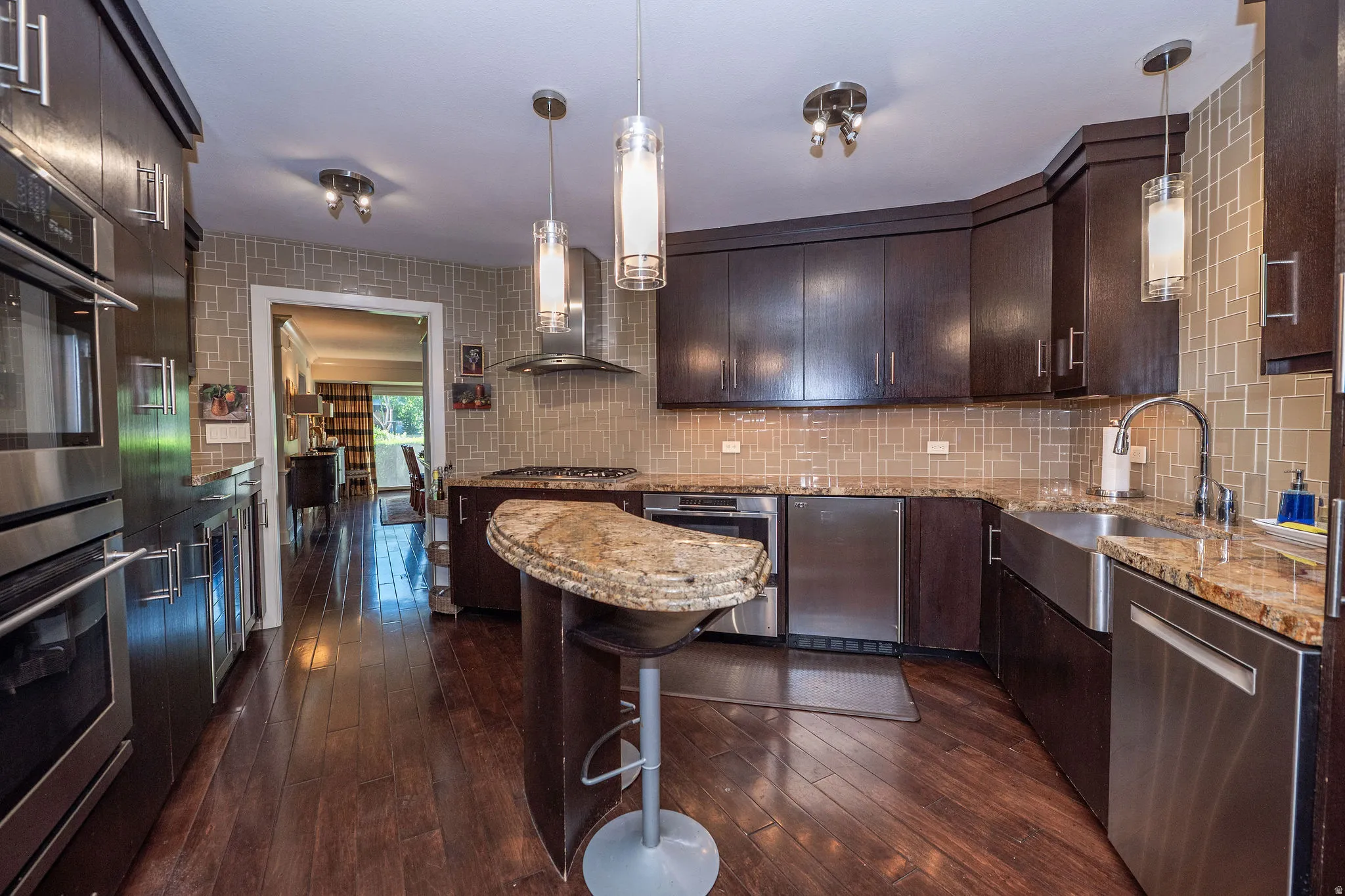 Gourmet kitchen featuring dark wood cabinetry, stainless steel appliances, granite countertops, and wood-finish flooring