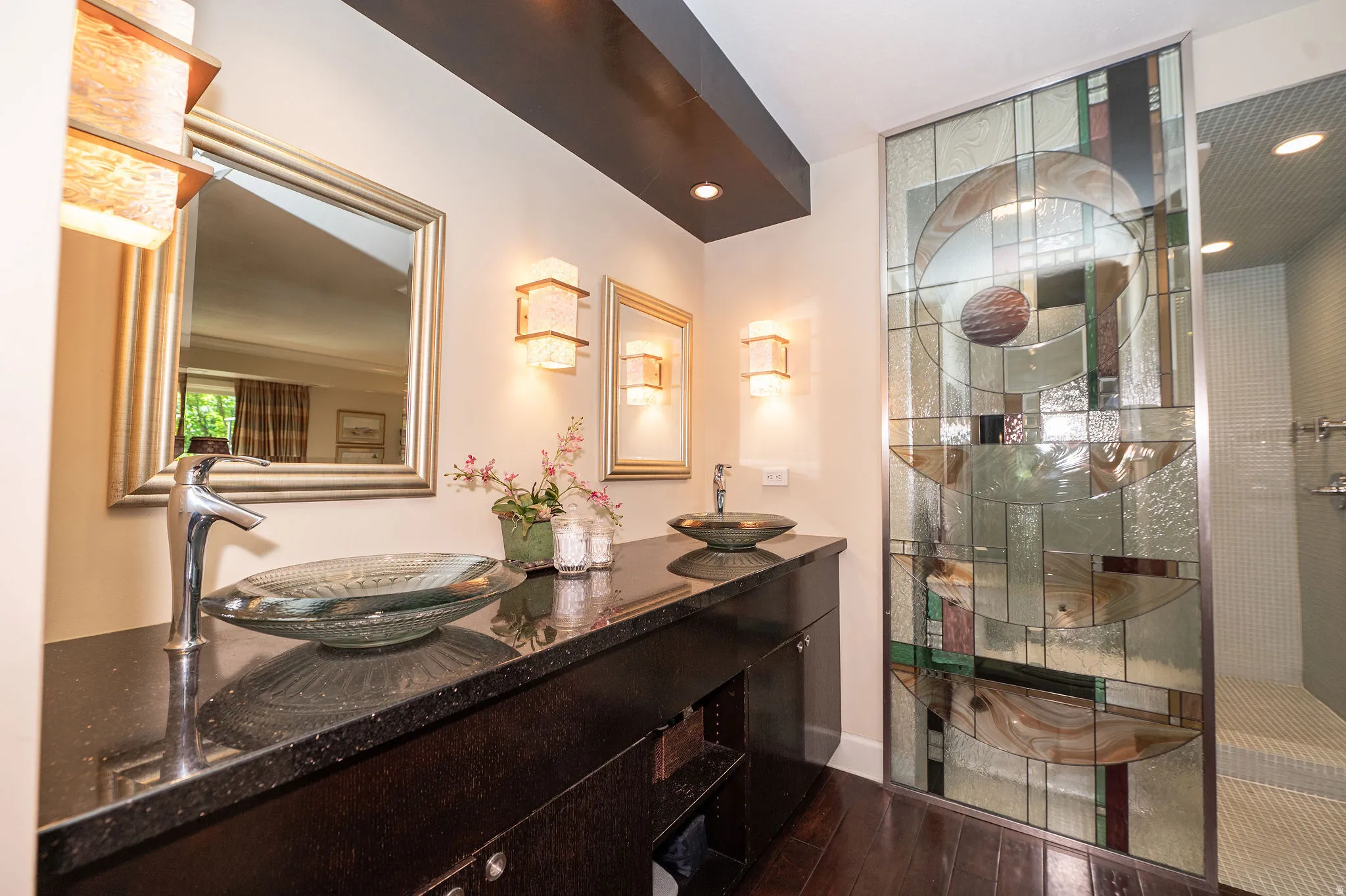 Dual vessel sinks set on a dark countertop with two framed mirrors