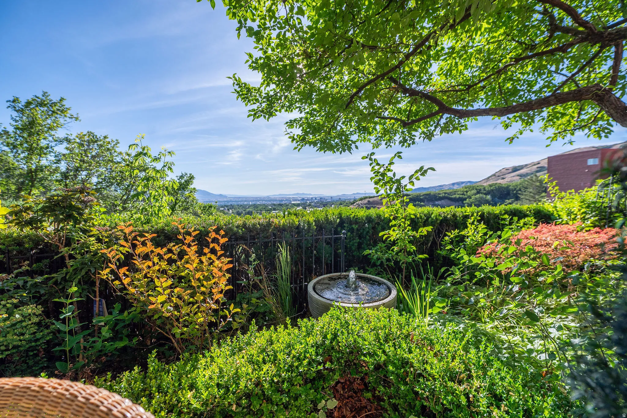 Lush garden landscaping featuring a water fountain, mature trees, and a distant city backdrop