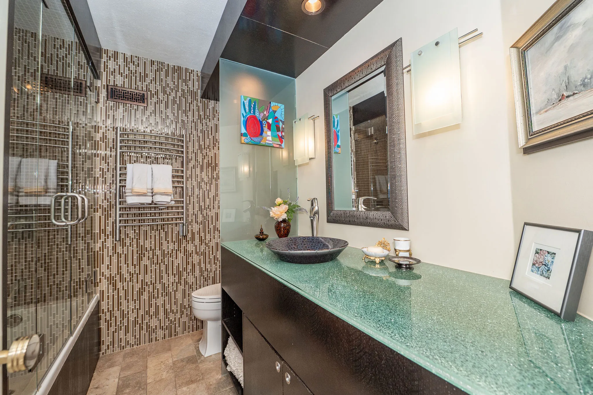Contemporary bathroom featuring a dark wood-finish vanity with a vessel sink and a textured glass countertop