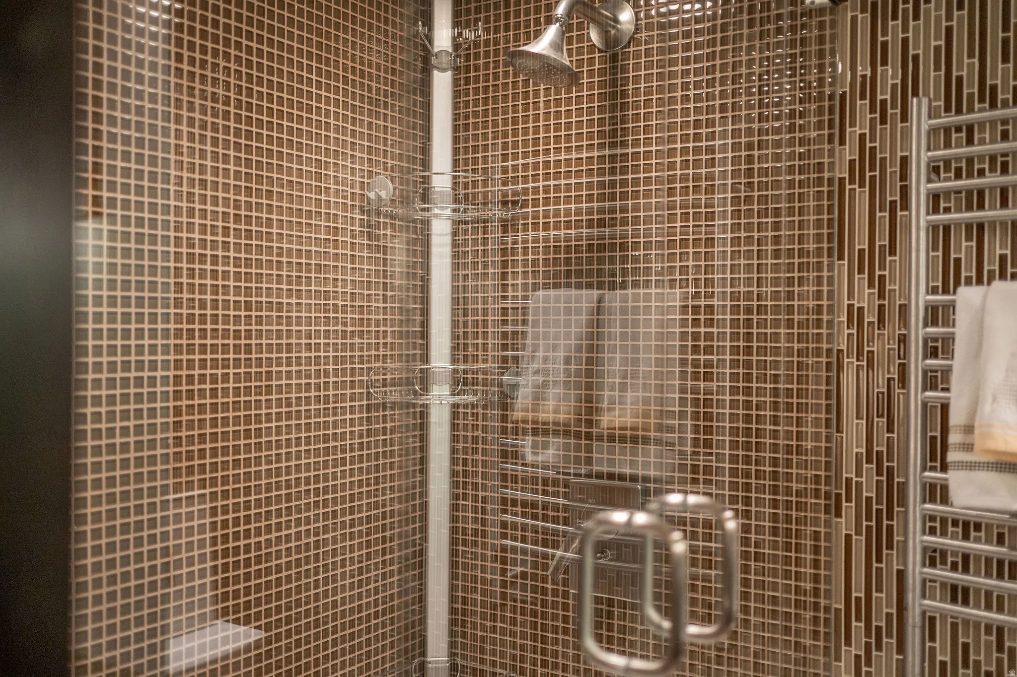 Enclosed shower featuring full-height mosaic tile, a satin nickel showerhead, and a clear glass enclosure with brushed metal handles