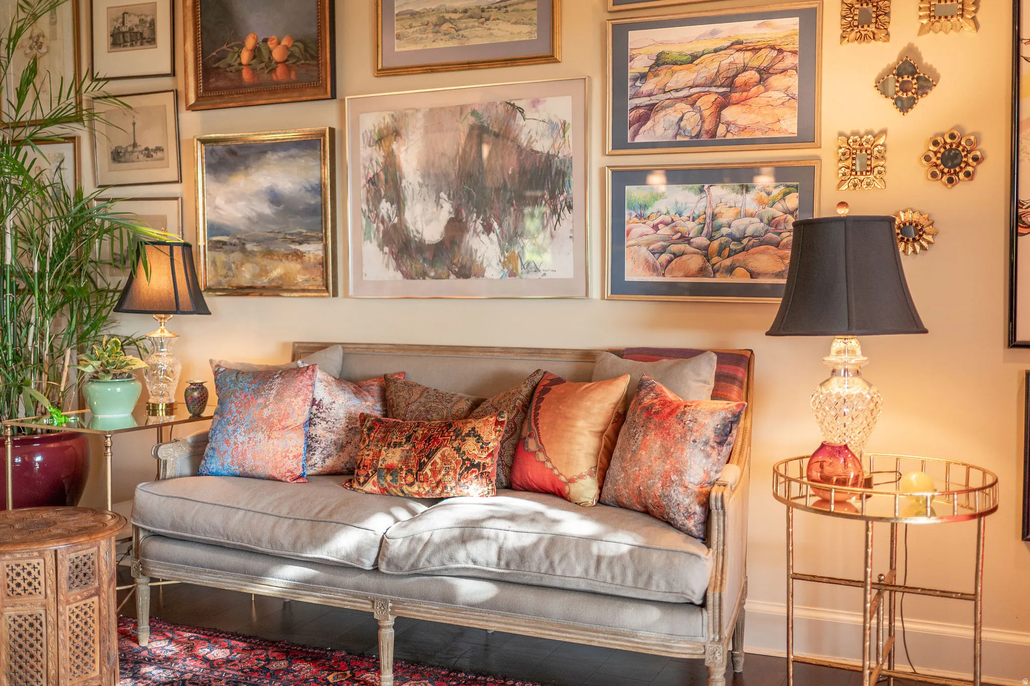 Wall-mounted art gallery with framed pieces and decorative accents above a light-toned settee